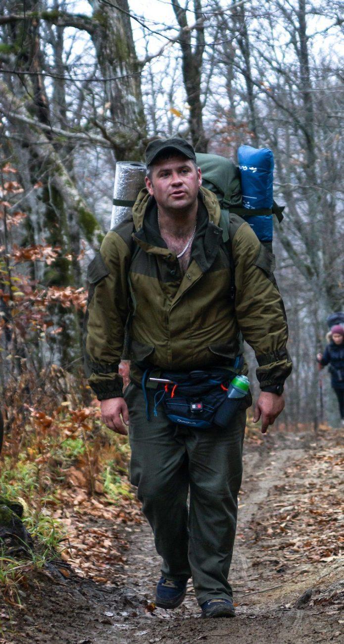 Путешественник идет в лесу с рюкзаком