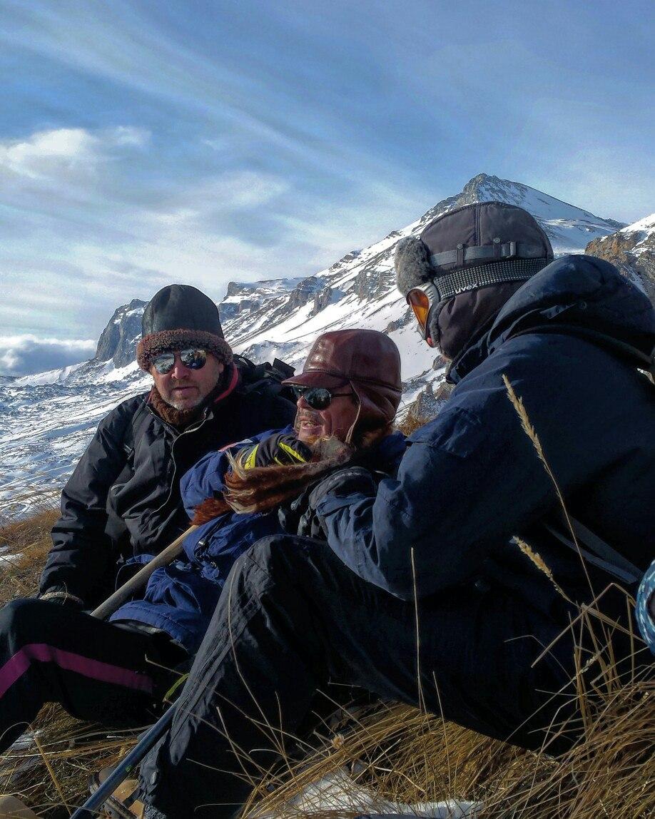 Три мужчины-туриста высоко в снежных горах и в солнечных очках отдыхают