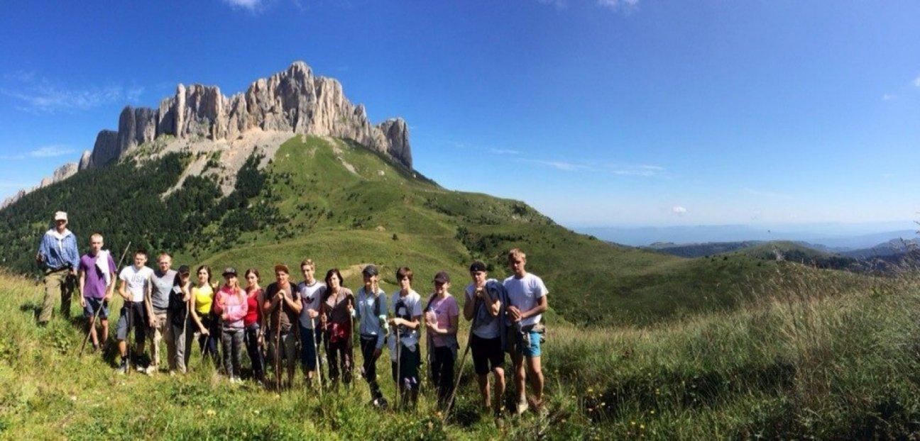 Группа туристов в горах фотографируется на фоне скалы