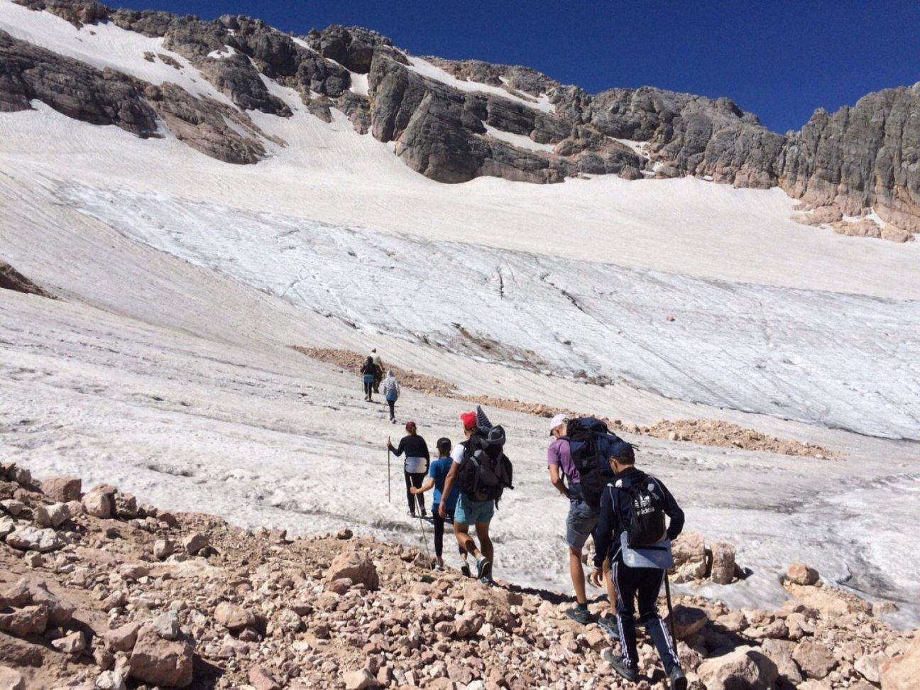 Группа туристов-путешественников поднимаются в крутую гору