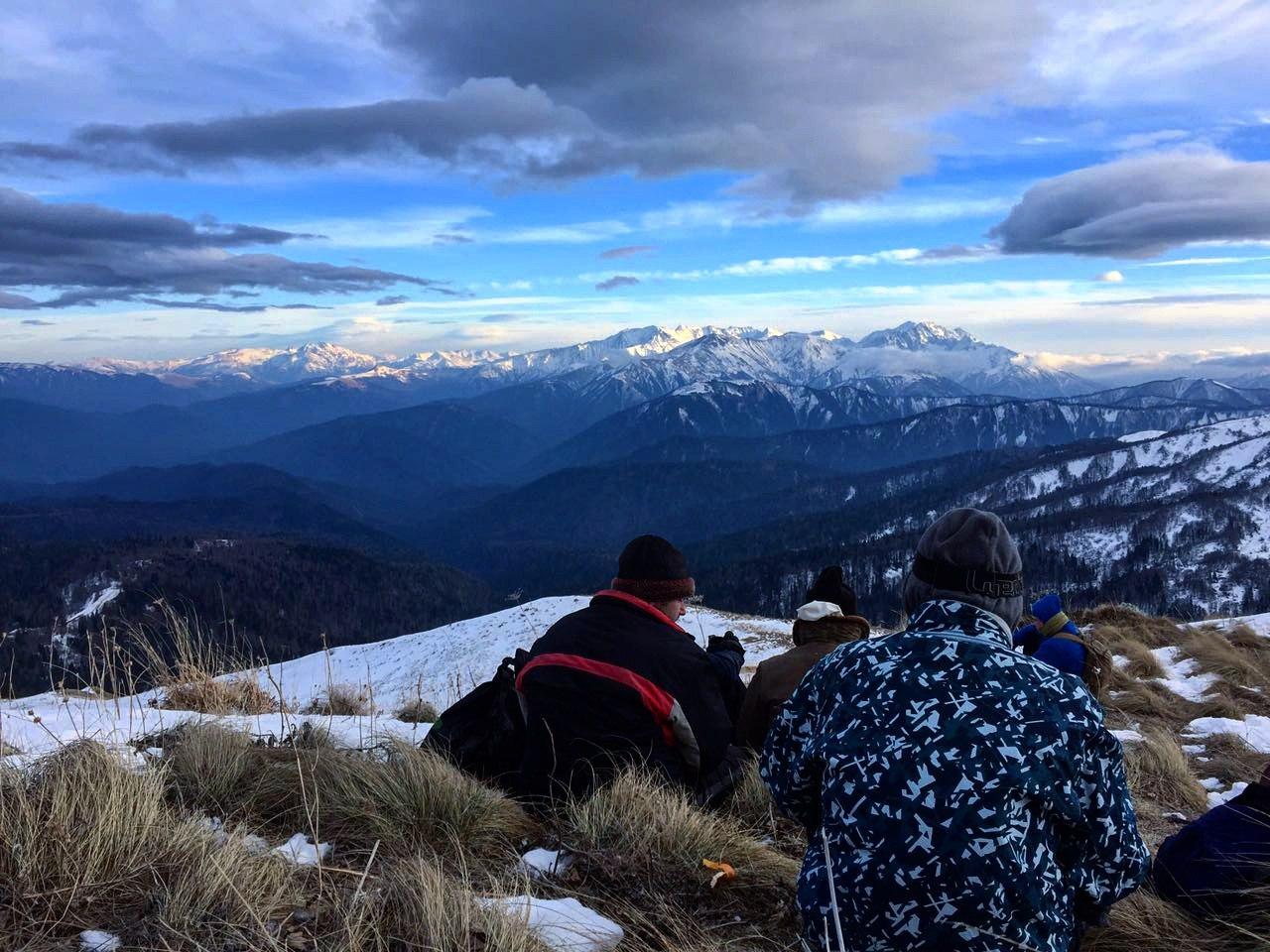 Ребята в горах отдыхают и фотографируются спинами на фоне снежных гор