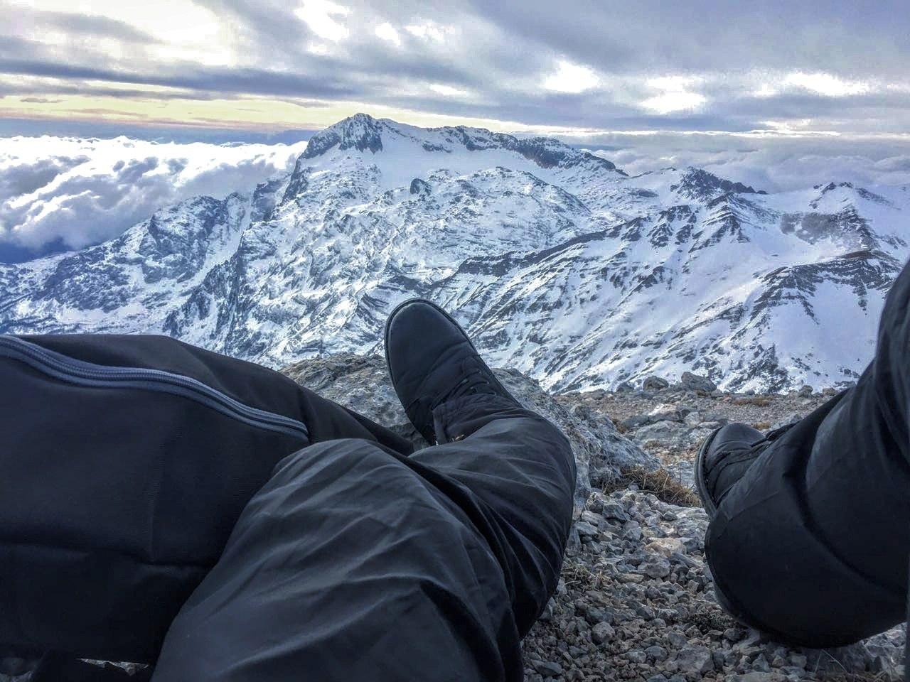 Ноги и рюкзак на фоне красивых снежных высоких гор